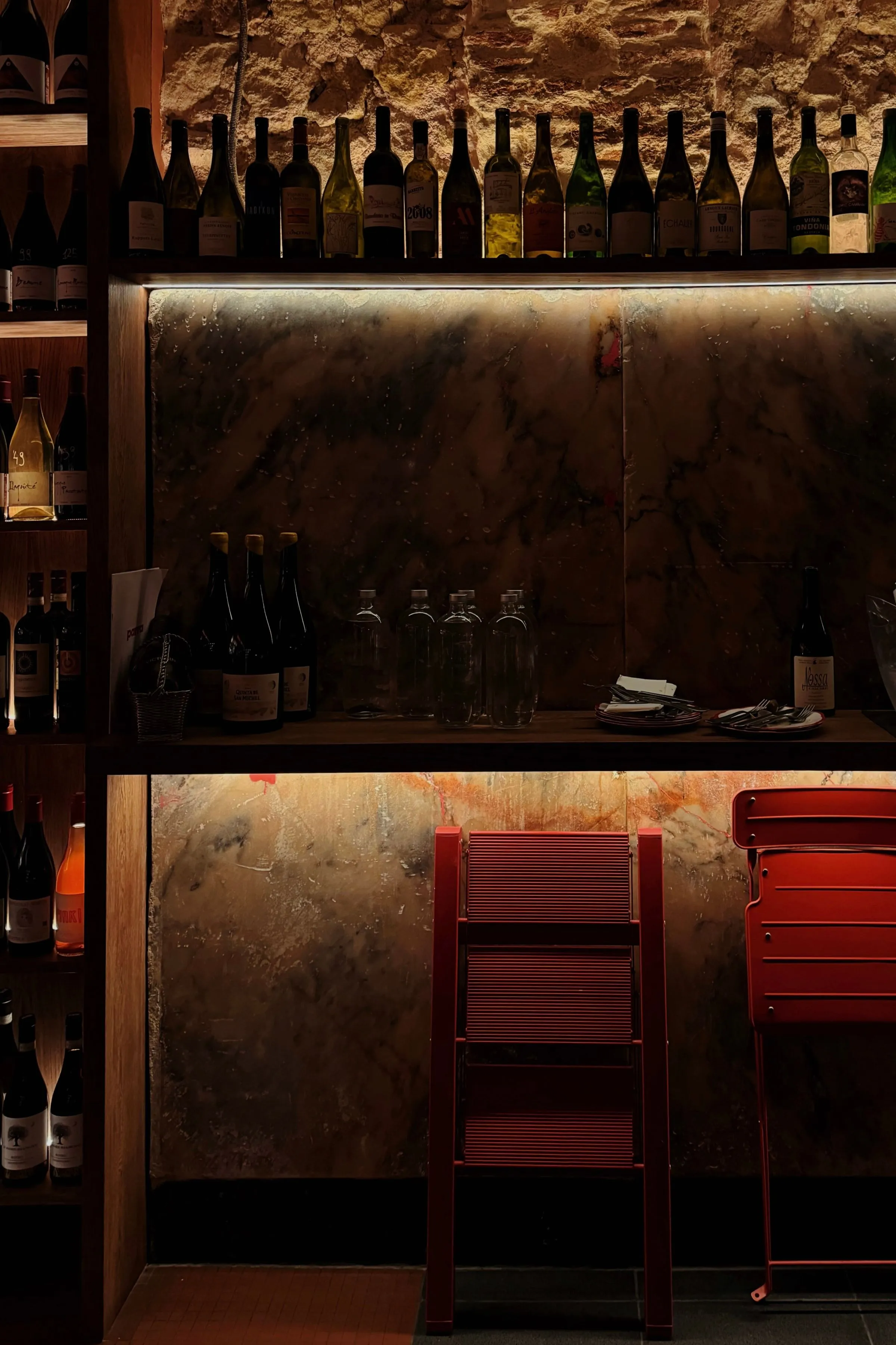 An intimate wine lounge lined with bottles and warm ambient light